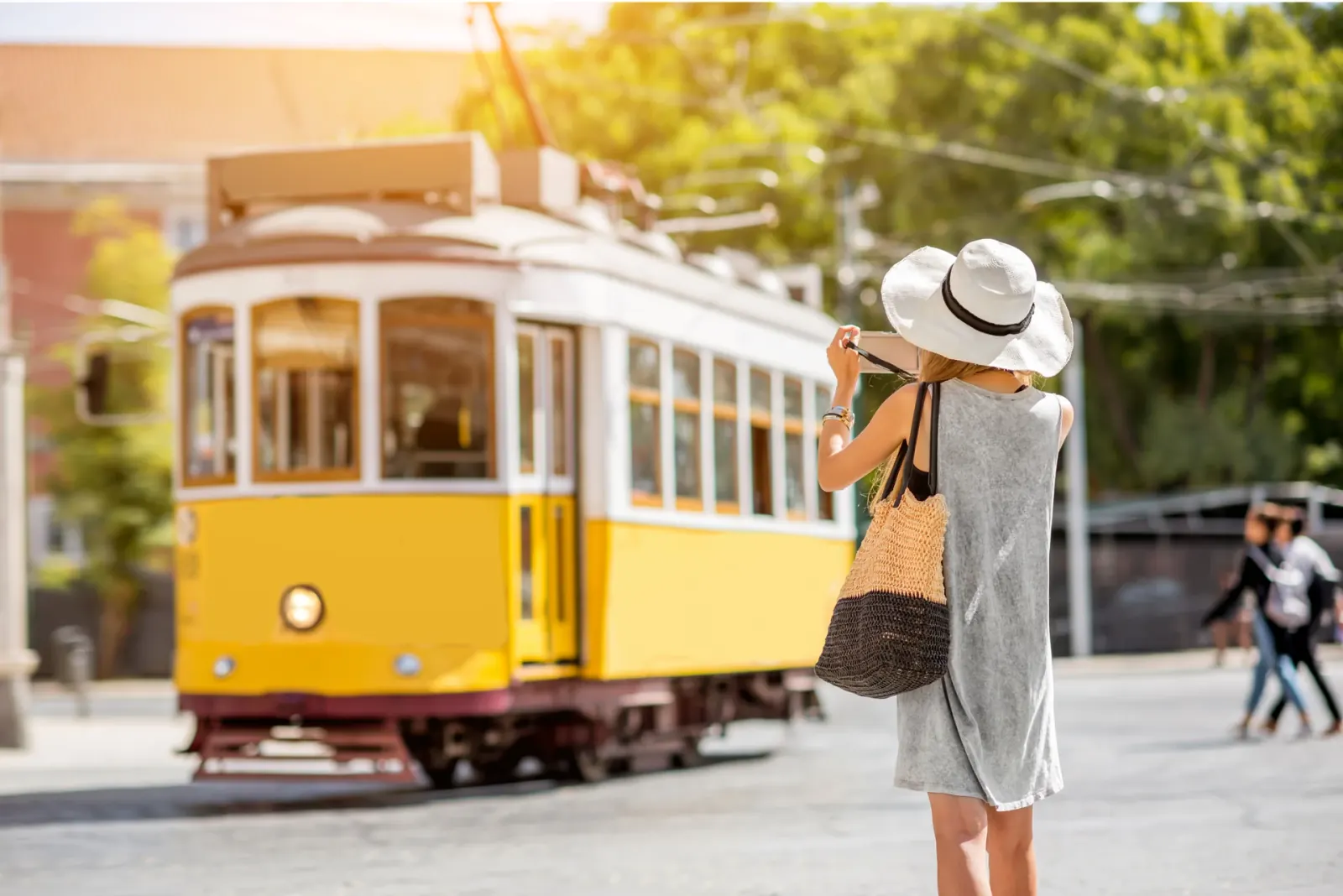 Mulher a fotografar o eléctrico amarelo em Lisboa
